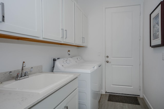 washroom with wood finished floors, independent washer and dryer, a sink, and cabinet space