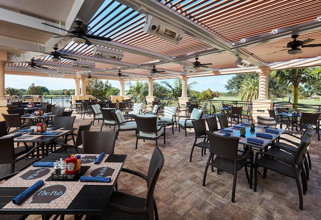 view of patio / terrace with a water view, a ceiling fan, a pergola, and outdoor dining space