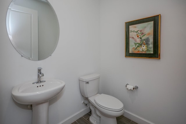 half bath featuring toilet and baseboards