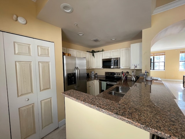 663 Hibiscus St, West Palm Beach, FL 33401 - kitchen featuring appliances with stainless steel finishes, sink, white cabinets, dark stone counters, and kitchen peninsula