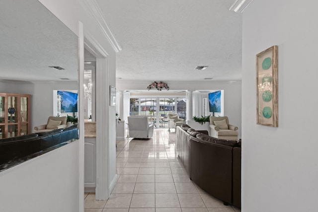 corridor featuring light tile patterned flooring, a textured ceiling, and ornate columns