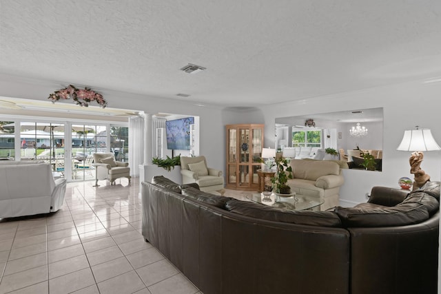 living room featuring a notable chandelier, decorative columns, a textured ceiling, and light tile patterned floors