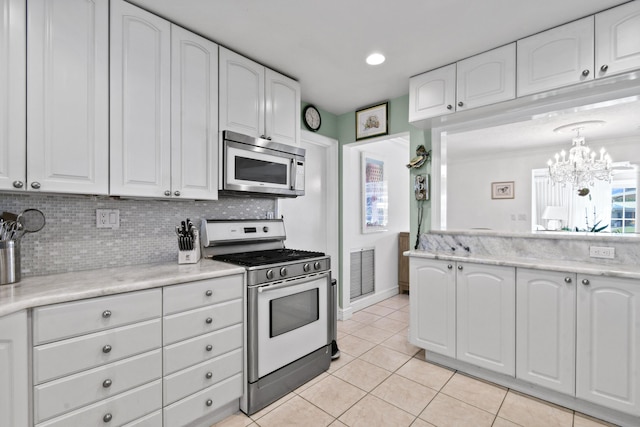 kitchen with backsplash, light tile patterned flooring, white cabinets, and appliances with stainless steel finishes