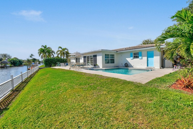 back of property with a fenced in pool, a lawn, a patio, and a water view