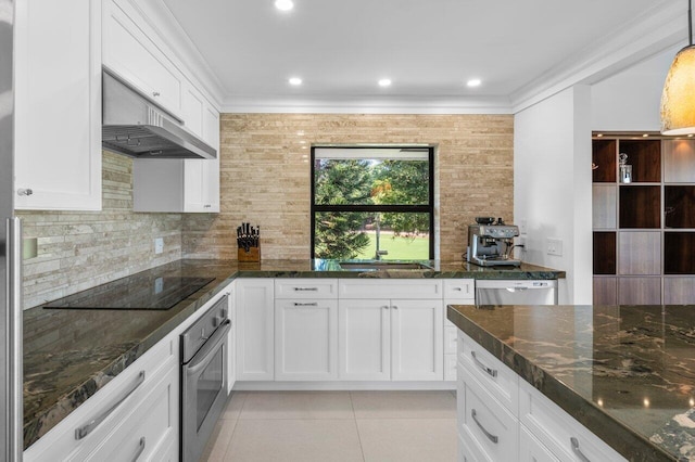 kitchen with appliances with stainless steel finishes, dark stone countertops, white cabinets, and range hood