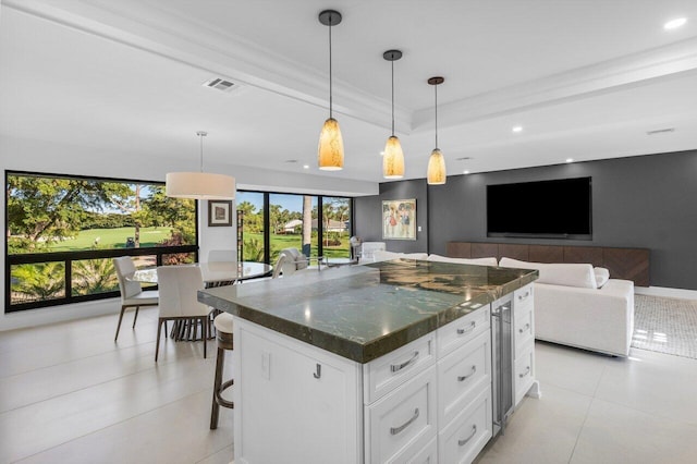 kitchen featuring pendant lighting, a breakfast bar, white cabinetry, dark stone countertops, and a center island