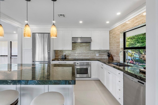 kitchen with white cabinets, stainless steel appliances, a kitchen bar, a sink, and exhaust hood