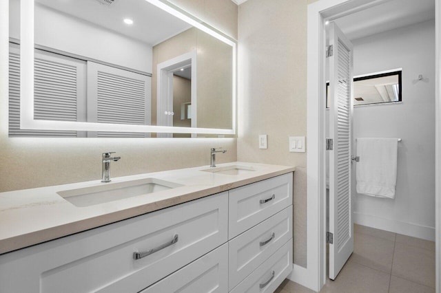 bathroom featuring double vanity, baseboards, a sink, and tile patterned floors