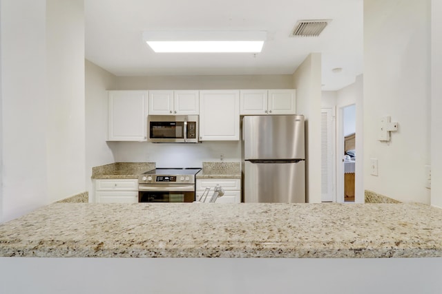 kitchen featuring light stone countertops, white cabinets, and appliances with stainless steel finishes