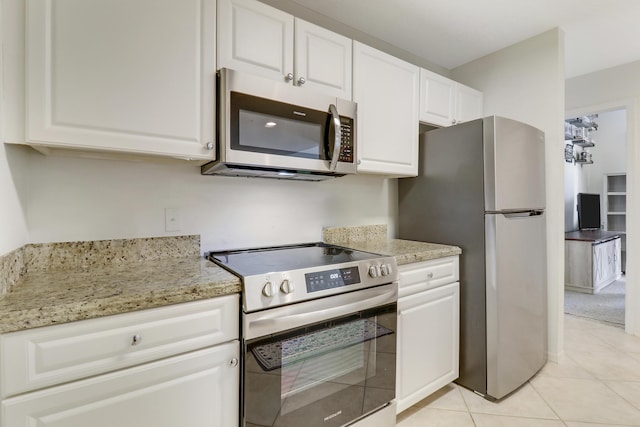 kitchen featuring light tile patterned floors, light stone countertops, white cabinets, and appliances with stainless steel finishes