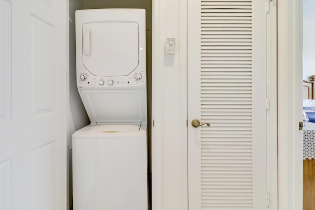 clothes washing area with stacked washing maching and dryer