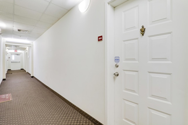 hallway with a drop ceiling and carpet floors