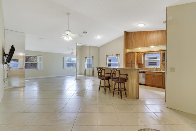 kitchen featuring ceiling fan, stainless steel dishwasher, a breakfast bar, and light tile patterned floors