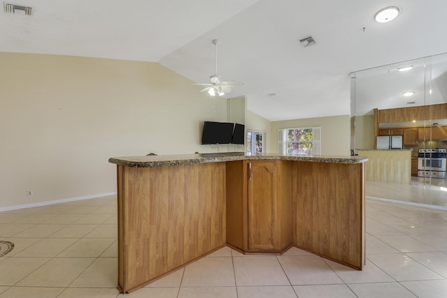 kitchen featuring lofted ceiling, light tile patterned floors, and stainless steel fridge