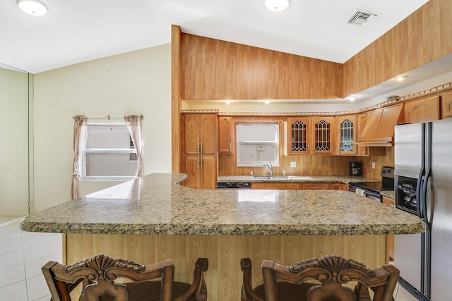 kitchen featuring vaulted ceiling, appliances with stainless steel finishes, sink, light tile patterned floors, and custom range hood