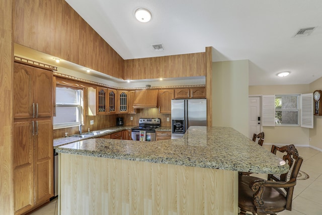 kitchen featuring sink, light tile patterned floors, a breakfast bar, appliances with stainless steel finishes, and extractor fan