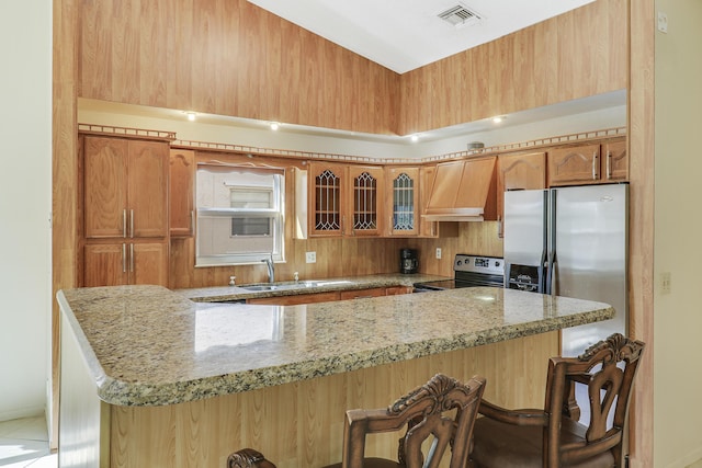 kitchen with premium range hood, appliances with stainless steel finishes, sink, a kitchen breakfast bar, and kitchen peninsula