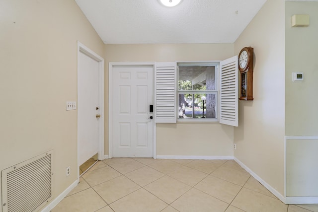 foyer entrance featuring a textured ceiling and light tile patterned floors