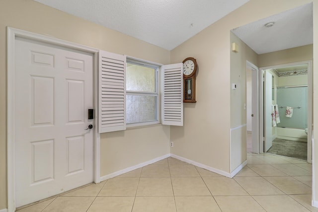 foyer entrance with a textured ceiling and light tile patterned flooring