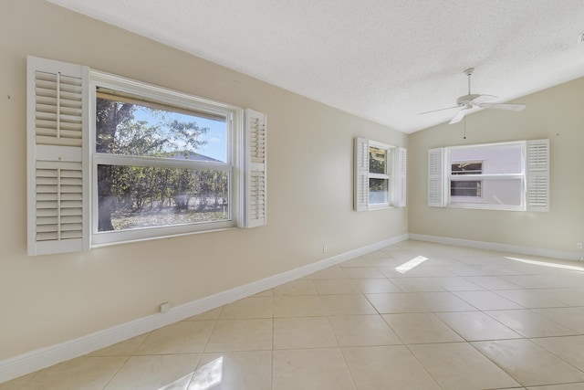 tiled empty room with vaulted ceiling, ceiling fan, and a textured ceiling