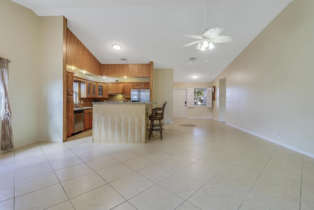 kitchen featuring a kitchen bar, high vaulted ceiling, light tile patterned floors, ceiling fan, and stainless steel appliances