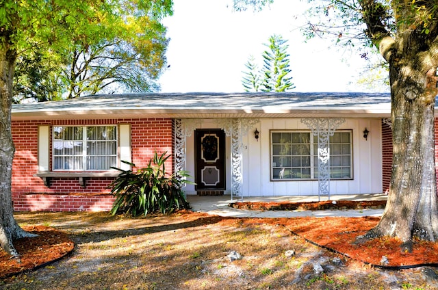 ranch-style house featuring brick siding, a porch, and board and batten siding