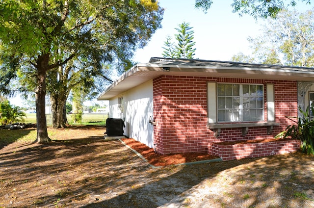 view of home's exterior with brick siding, central AC, and fence