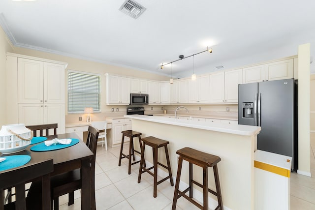 kitchen with a kitchen island with sink, light tile patterned floors, pendant lighting, and stainless steel appliances