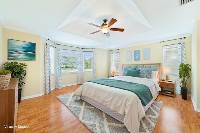 bedroom featuring a tray ceiling, light hardwood / wood-style flooring, ornamental molding, and ceiling fan