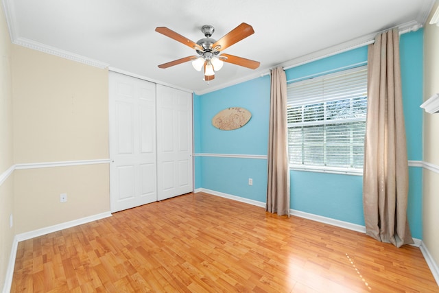 unfurnished bedroom with crown molding, light wood-type flooring, and a closet