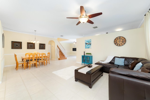 tiled living room with ceiling fan with notable chandelier