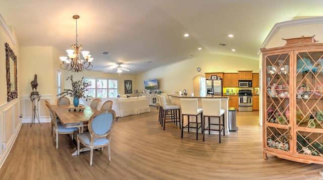 dining space with vaulted ceiling, ceiling fan with notable chandelier, and light wood-type flooring