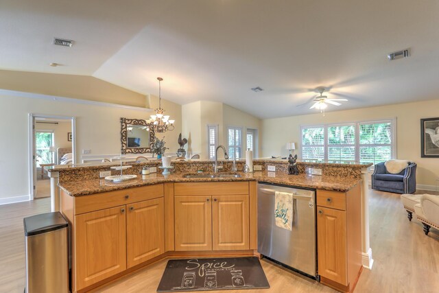 kitchen featuring lofted ceiling, sink, stone counters, decorative light fixtures, and stainless steel dishwasher