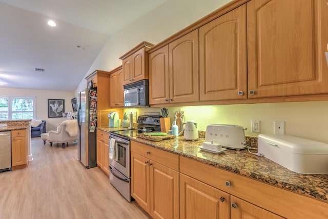 kitchen featuring lofted ceiling, light hardwood / wood-style flooring, dark stone counters, and appliances with stainless steel finishes