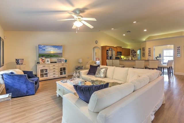 living room with ceiling fan, lofted ceiling, and light wood-type flooring