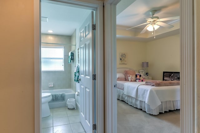 bedroom featuring a raised ceiling, ensuite bathroom, light tile patterned floors, and ceiling fan