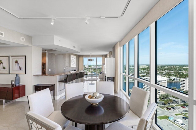 dining area with light tile patterned flooring, a water view, rail lighting, and visible vents