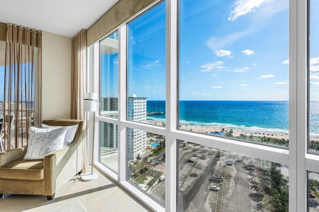 unfurnished sunroom with a water view, a beach view, and a wealth of natural light