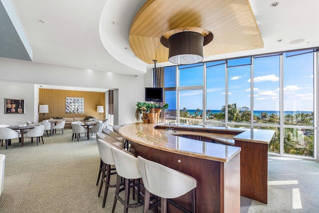 kitchen with expansive windows, a raised ceiling, and light colored carpet