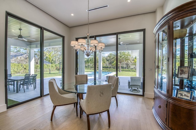 dining space with ceiling fan with notable chandelier and light hardwood / wood-style floors