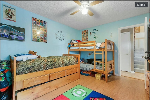 bedroom with hardwood / wood-style flooring, ceiling fan, and a textured ceiling