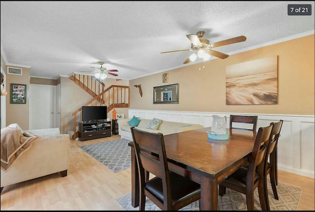 dining space featuring crown molding, a textured ceiling, and light hardwood / wood-style floors