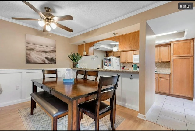 dining area with ceiling fan, ornamental molding, and a textured ceiling