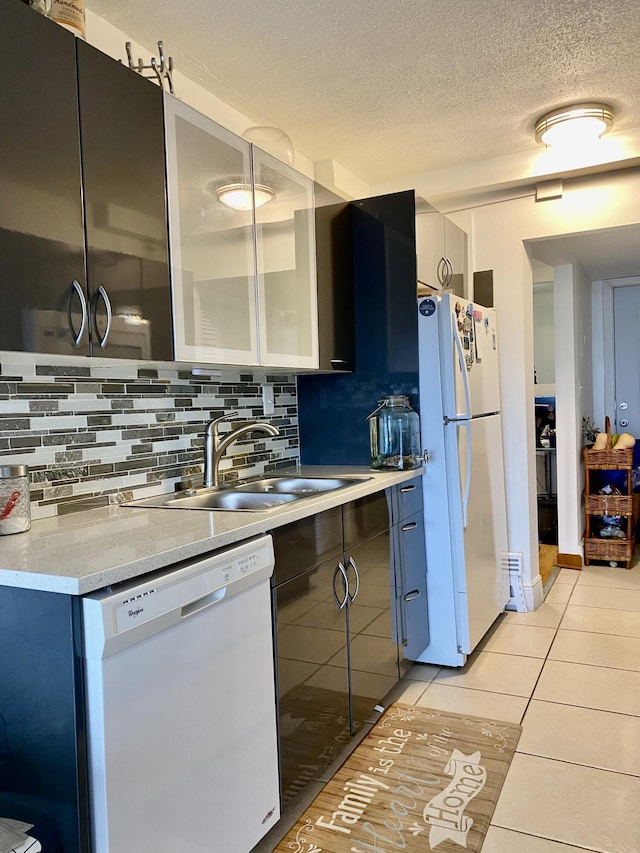 kitchen with sink, white appliances, light tile patterned floors, tasteful backsplash, and a textured ceiling