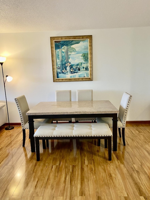 dining room with light hardwood / wood-style floors and a textured ceiling