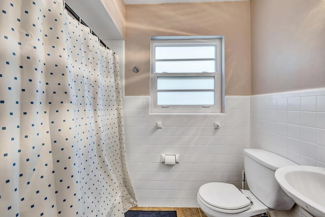 bathroom featuring a shower with shower curtain, sink, and tile walls