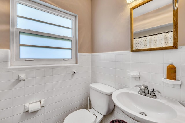 bathroom featuring toilet, sink, and tile walls