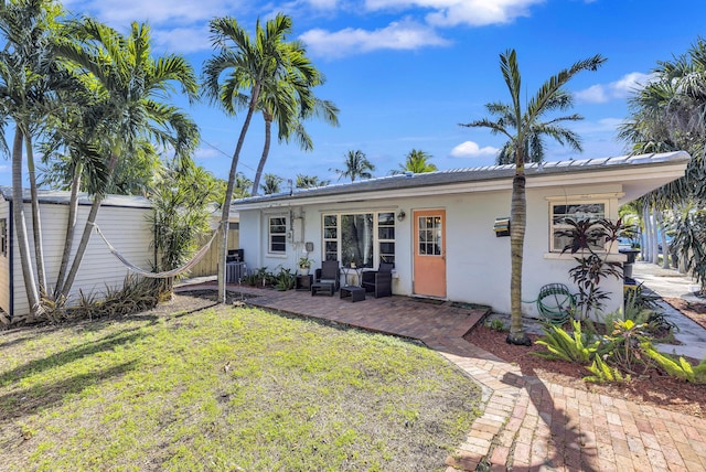 rear view of house with a patio, cooling unit, and a lawn