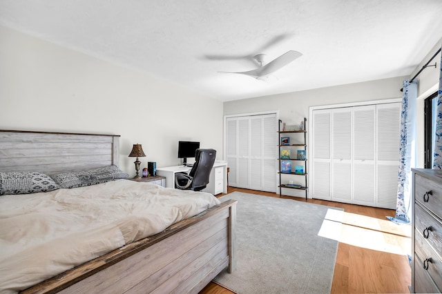 bedroom featuring two closets, a textured ceiling, ceiling fan, and light wood-type flooring