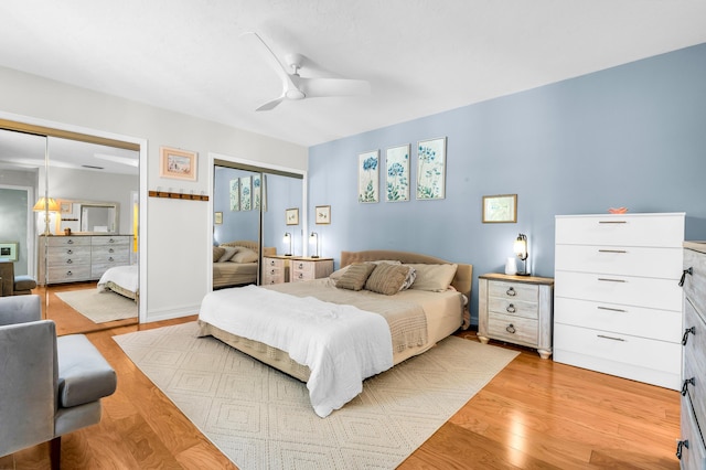 bedroom with two closets, ceiling fan, and light hardwood / wood-style flooring